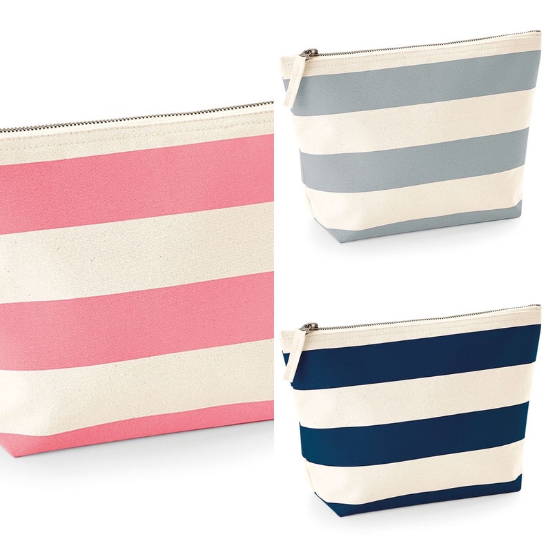 May include: Three striped zippered pouches. The pouches are made of canvas and have a white background with colored stripes. The pouches are pink, light blue, and navy blue.