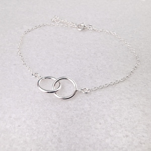 Könnte beinhalten: Ein silbernes Kettenarmband mit einem zarten Design aus ineinandergreifenden Kreisen.