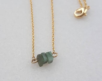 May include: A gold chain necklace with three small, rectangular green gemstones.