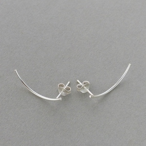 May include: A pair of silver curved stud earrings. The earrings are made of a thin, curved piece of metal that is attached to a post.