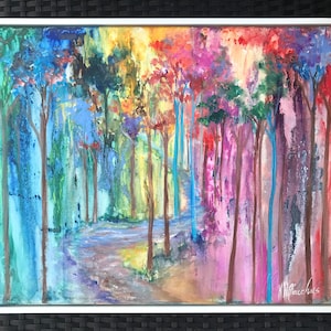 May include: A colourful abstract painting of a forest with a path leading through the trees. The trees are painted in shades of blue, green, yellow, orange, red, and purple. The path is a light brown colour. The painting is framed in a black frame.