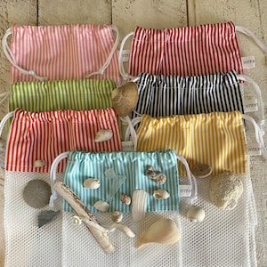 May include: A collection of seven rectangular drawstring pouches featuring vertical stripes in pink, red, lime green, navy blue, orange, yellow, and light blue. Each pouch has a white mesh bottom and a small white tag labeled "winkle".