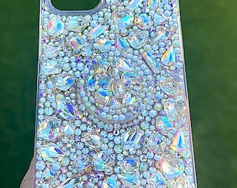 May include: A clear phone case covered in iridescent rhinestones of various shapes and sizes.