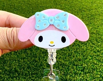 Puede incluir: Carrete de identificación de Hello Kitty rosa y azul con un cordón retráctil transparente y un clip giratorio plateado.