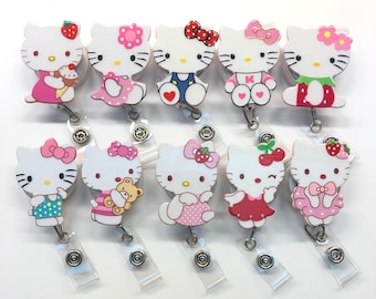 Könnte beinhalten: Zehn Hello Kitty-Ausweishalter mit verschiedenen Designs. Jeder Halter zeigt ein Hello Kitty-Motiv mit verschiedenen Outfits und Accessoires. Die Halter sind aus klarem Kunststoff und haben einen Metallclip.