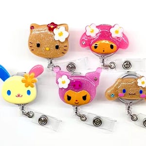May include: Five character-themed retractable badge holders. The characters include a yellow bunny with blue and pink ears, a pink cat, a brown cat, a pink pig, and a brown cat. Each badge holder has a flower accent and a clear plastic clip.