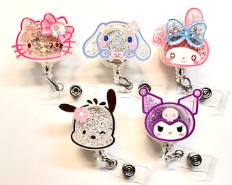 May include: Five colorful character badge holders with glitter and rhinestones. The characters are Hello Kitty, My Melody, Kuromi, Cinnamoroll, and Pompompurin.