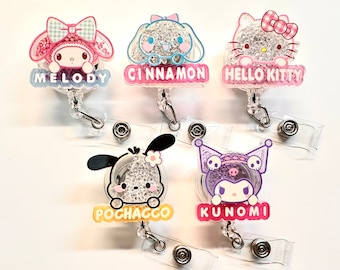 Könnte beinhalten: Fünf bunte Charakter-Ausweishalter mit Glitzer und Strasssteinen. Die Charaktere sind Hello Kitty, Melody, Cinnamoroll, Pochacco und Kunoomi.