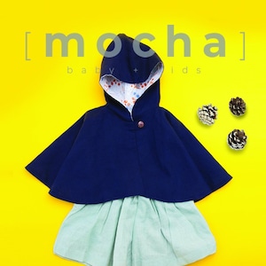 May include: A navy blue hooded cape with a floral lining, paired with a light green skirt. The cape has a button closure and is made of a soft, comfortable fabric. [mocha] baby + kids
