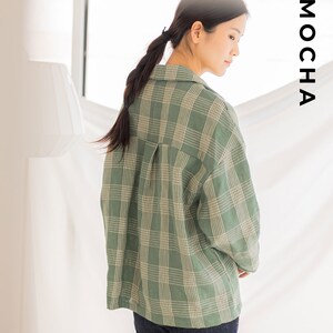 Peut inclure: Une chemise &agrave; carreaux verts et blancs &agrave; manches longues et &agrave; boutonni&egrave;re. La chemise est ample et de style d&eacute;contract&eacute;. Le mannequin porte la chemise avec le col relev&eacute; et les manches retrouss&eacute;es.