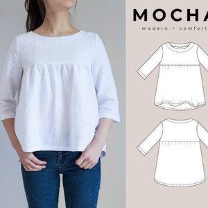 May include: A white linen top with a gathered waist and 3/4 sleeves. The top is shown on a model wearing blue jeans. The text "MOCHA modern + comfort" is shown in the upper right corner of the image.