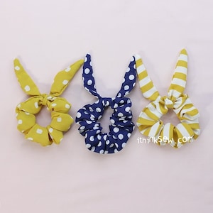Może przedstawiać: Trzy scrunchies do włosów w różnych wzorach. Jeden jest żółty w białe kropki, drugi jest granatowy w białe kropki, a trzeci jest w żółto-białe paski.