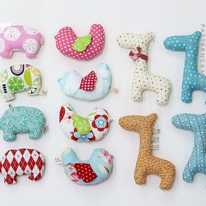 May include: Ten handmade plush toys in various animal shapes and patterns. The toys include a pink pig, a blue and white bird, a green and white elephant, a blue and white elephant, a red and white elephant, a yellow and white giraffe, a blue and white giraffe, a blue and white horse, a yellow and white giraffe, and a blue and white bird.