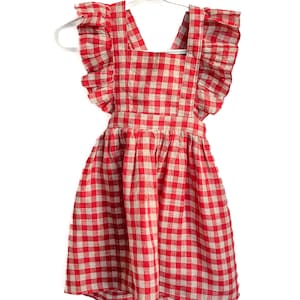 May include: Red and white gingham dress with ruffled straps. The dress has a sleeveless design and a full skirt.