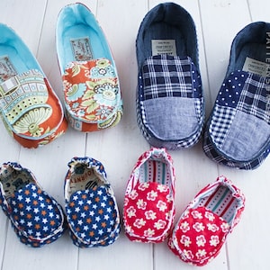 May include: A set of six colorful fabric baby shoes. The shoes are made of different patterned fabrics, including floral, plaid, and polka dots. The shoes are all in different colors, including blue, red, and green.