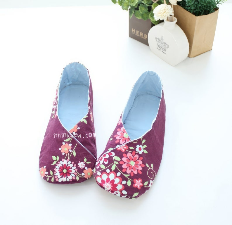 May include: A pair of plum-colored slippers with a floral pattern in pink, white, and green. The slippers have a light blue interior and a wrap-around design. The text "ithinksew.com" is visible on the side of one slipper.