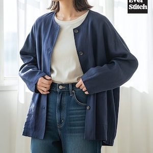 Pode incluir: Casaco azul marinho com gola redonda, usado sobre uma camiseta branca e jeans azuis. O casaco tem três botões visíveis e dois bolsos. O logotipo Ever Stitch está no canto superior direito.