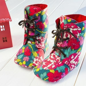 May include: A pair of floral print ankle boots with brown laces. The boots are teal blue with pink, red, and yellow flowers.