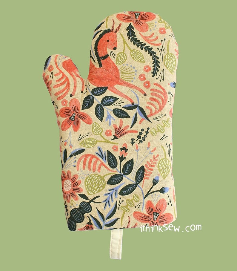 May include: A red and green floral print oven mitt with a stylised deer design. The mitt has a hanging loop and the text "ithinksew.com" is printed on the bottom.