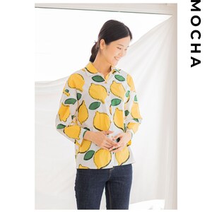 Peut inclure: Une chemise blanche &agrave; manches longues avec un imprim&eacute; citron. La chemise a un col boutonn&eacute; et des manches longues. Le mannequin porte un jean bleu.