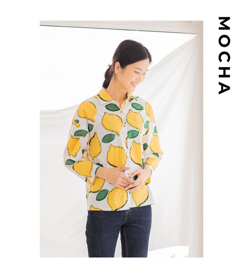 Peut inclure: Une chemise blanche &agrave; manches longues avec un imprim&eacute; citron. La chemise a un col boutonn&eacute; et des manches longues. Le mannequin porte un jean bleu.