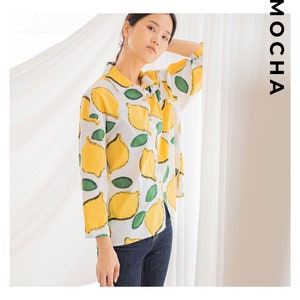 Peut inclure: Une chemise boutonn&eacute;e blanche &agrave; imprim&eacute; citron. La chemise a des manches longues et un col.