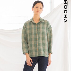 Peut inclure: Une chemise boutonn&eacute;e &agrave; manches longues &agrave; carreaux verts et blancs. La chemise est faite d'un tissu l&eacute;ger et a une coupe d&eacute;contract&eacute;e.