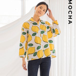 Peut inclure: Une chemise boutonn&eacute;e blanche &agrave; imprim&eacute; citron. La chemise a des manches longues et une coupe ample. Le mannequin porte un jean bleu.