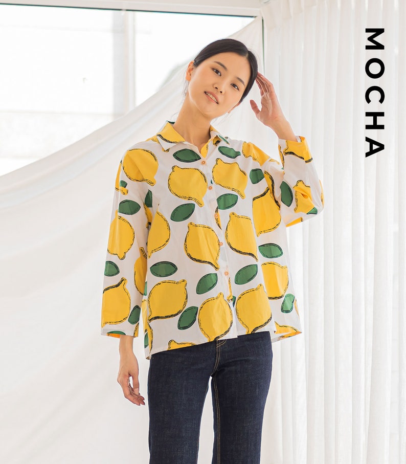 Peut inclure: Une chemise boutonn&eacute;e blanche &agrave; imprim&eacute; citron. La chemise a des manches longues et une coupe ample. Le mannequin porte un jean bleu.