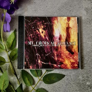 Può includere: Un'astuccio per CD con il testo "MY CHEMICAL ROMANCE" e il titolo dell'album "I BROUGHT YOU MY BULLETS, YOU BROUGHT ME YOUR LOVE." La copertina presenta un design astratto scuro con sfumature rosse e gialle.