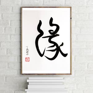 May include: Black and white calligraphy art print of the Japanese word "感" (kan) meaning "feeling" or "emotion". The print is framed and has a red seal with the artist's signature.