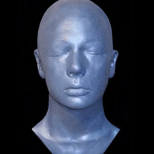 May include: A plaster cast of a person's head and neck, with the eyes closed. The cast is painted a light blue colour.