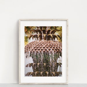 May include: A close-up of a pineapple-shaped fountain with water cascading down the sides. The fountain is made of brown material with gold accents. The water is clear and sparkling.