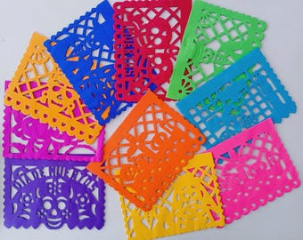 May include: A selection of vibrant papel picado banners in diverse colours and patterns. The banners, in shades of blue, red, green, orange, yellow, pink, and purple, feature intricate cut-out designs, including floral and skull motifs.