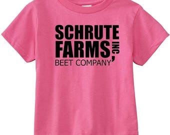 May include: Pink t-shirt with black text that reads "Schrute Farms, Inc. Beet Company"