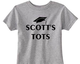 May include: Gray toddler t-shirt with black text that reads "SCOTT'S TOTS" and a black graduation cap graphic.