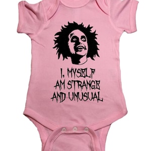 Puede incluir: Un body rosa para bebé con una imagen en blanco y negro de un personaje de la película "Beetlejuice" y el texto "I, Myself Am Strange And Unusual".