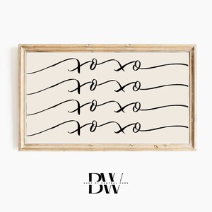May include: A framed wall art print with the word "xoxo" repeated in black script on a cream background. The wooden frame has a natural finish. The bottom of the print has the text "DW / DW".