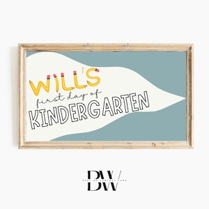 May include: A framed print with the text "WILL'S first day of KINDERGARTEN". The word "WILL'S" is styled with yellow pencil illustrations. The background features a light blue and white design, all within a wooden frame. A perfect gift for a child.