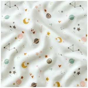 May include: A white fabric featuring a repeating celestial pattern of yellow crescent moons, teal and brown planets with rings, various sizes of stars, small orange hearts, and dotted constellation lines scattered across the surface.