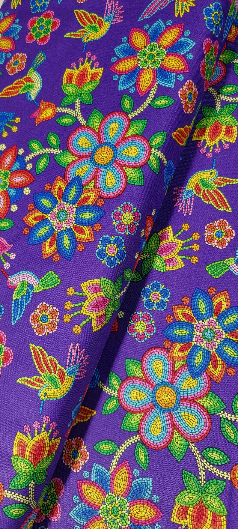 May include: Purple fabric with a repeating pattern of colorful flowers and hummingbirds. The flowers are made of small, colorful beads and the hummingbirds are outlined in black.