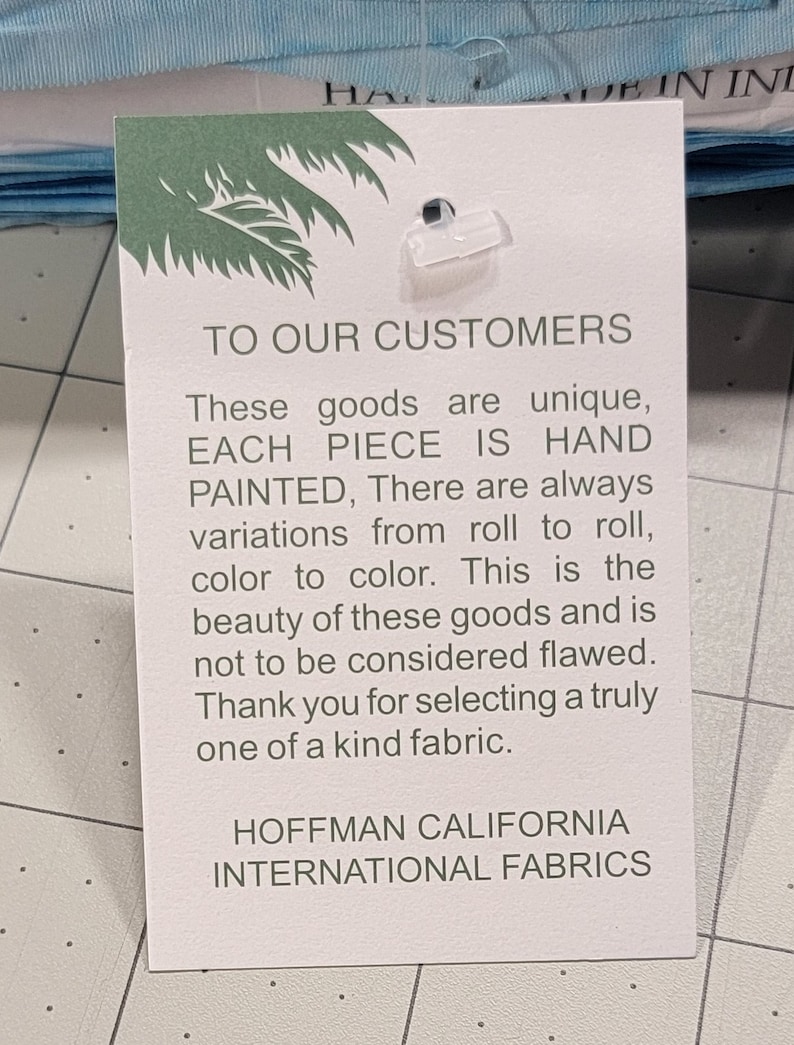 May include: A white tag with green text and a palm tree logo. The tag reads "TO OUR CUSTOMERS" and describes the unique, hand-painted fabric. The tag is from HOFFMAN CALIFORNIA INTERNATIONAL FABRICS.