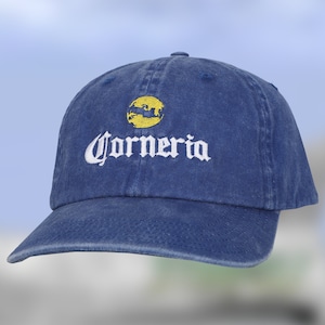 May include: A blue denim baseball cap with a yellow circle and the word "Corona" embroidered in white.