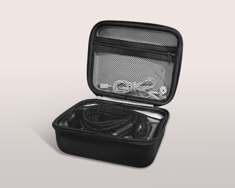 May include: Black, zippered carrying case, open to reveal contents. The case has a mesh pocket in the lid and contains black cables and white cords. The case is designed to protect and organize electronic accessories.