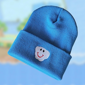May include: A blue beanie with a white smiling cloud embroidered on the front.