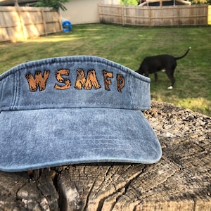 May include: A blue denim visor with the text "WSMFP" embroidered in brown on the front.