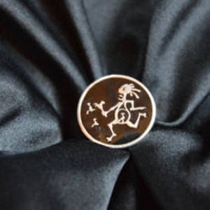 May include: A black and white enamel pin featuring a stylized stick figure dancing. The pin is circular and has a shiny finish.