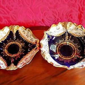 May include: Two decorative porcelain bowls with gold trim and intricate designs. The bowls are cobalt blue with white and gold accents.