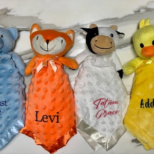 Peut inclure: Quatre couvertures pour b&eacute;b&eacute; en peluche avec des attaches de t&ecirc;te d'animaux. Les couvertures sont bleues, orange, blanches et jaunes. Les animaux sont un ours, un renard, une vache et un canard. Les couvertures sont personnalis&eacute;es avec les noms : August Lee, Levi, Tatum Grace et Addalyn.