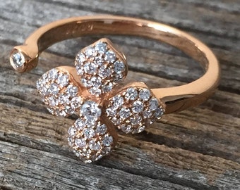 May include: A rose gold ring with a flower design set with small clear stones.